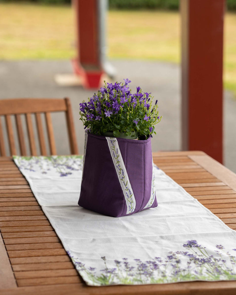 plante dans un cache-pot tissu violet sur un chemin de table fleurs de lavande violet 