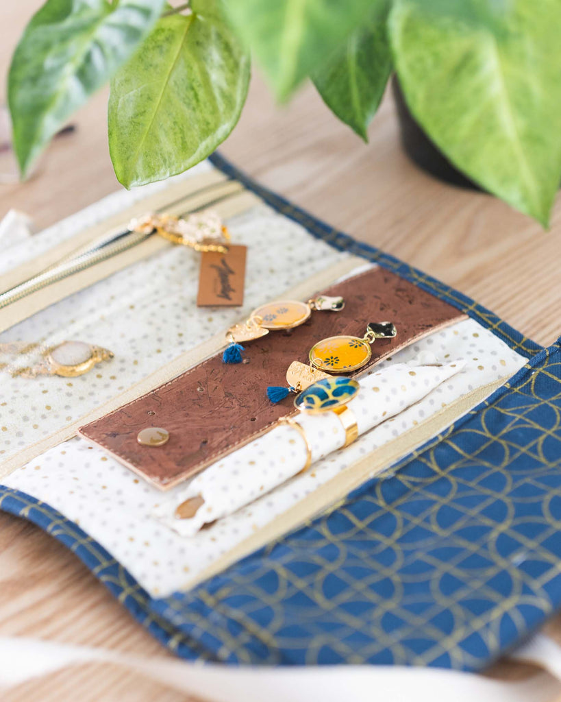 Trousse à bijoux marine, ouverte, avec compartiments : poche zippée cristal, support en liège pour boucles d’oreilles, boudin amovible pour bagues.