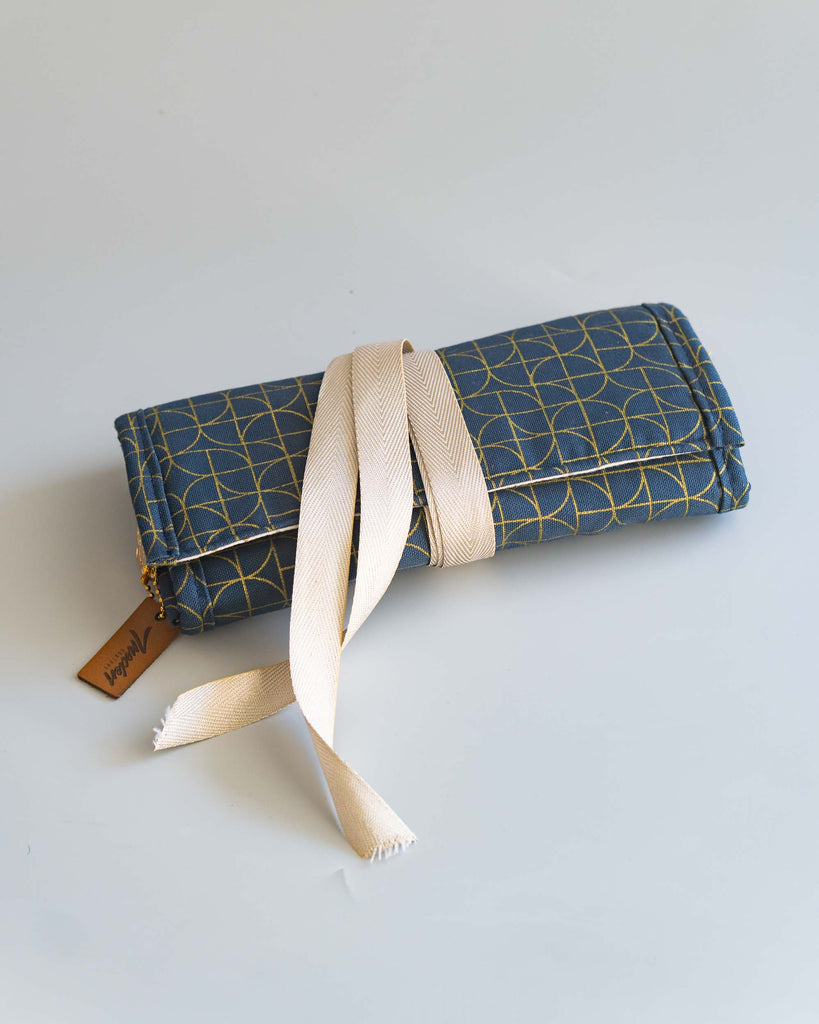 Pochette en tissu bleu et or fermée par un ruban écru