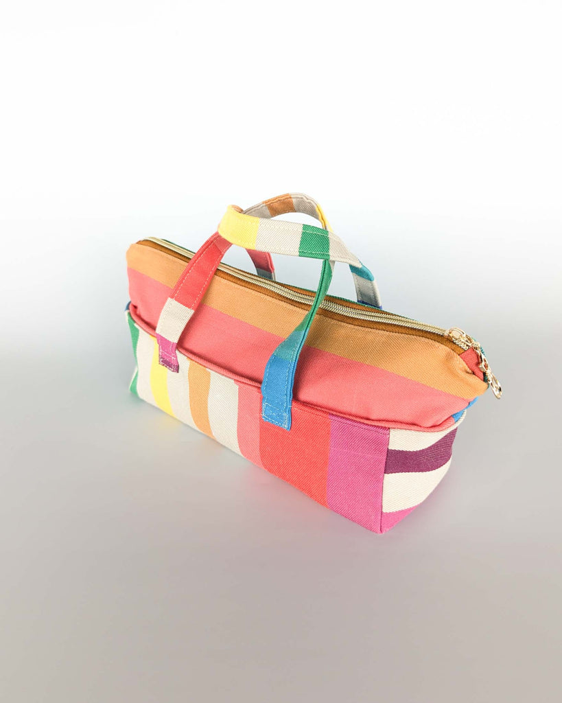 Trousse Argia en tissu basque multicolore, posée fermée avec ses deux anses visibles.