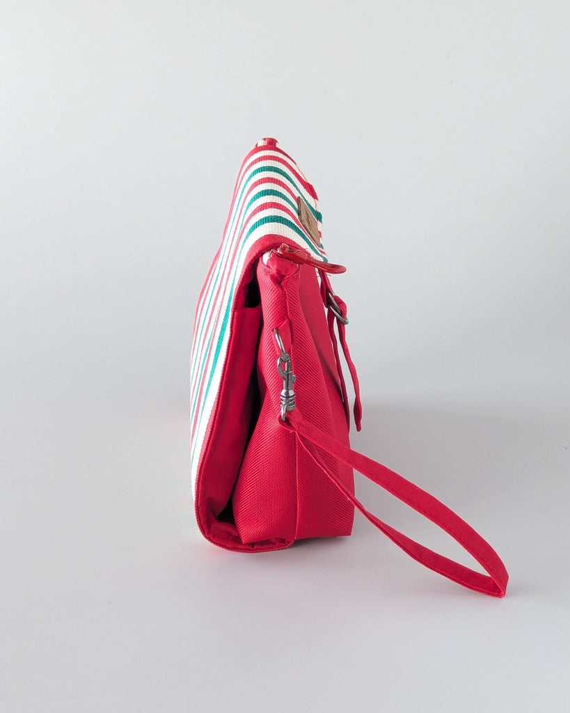 Trousse maquillage rouge de profil, avec rabat en Toile Basque rayée verte et blanche.