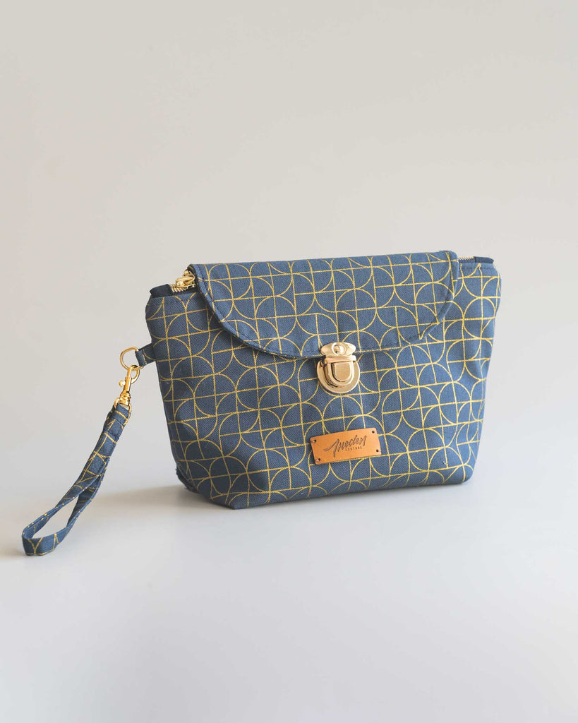 Pochette maquillage avec rabat fermé et dragonne amovible.