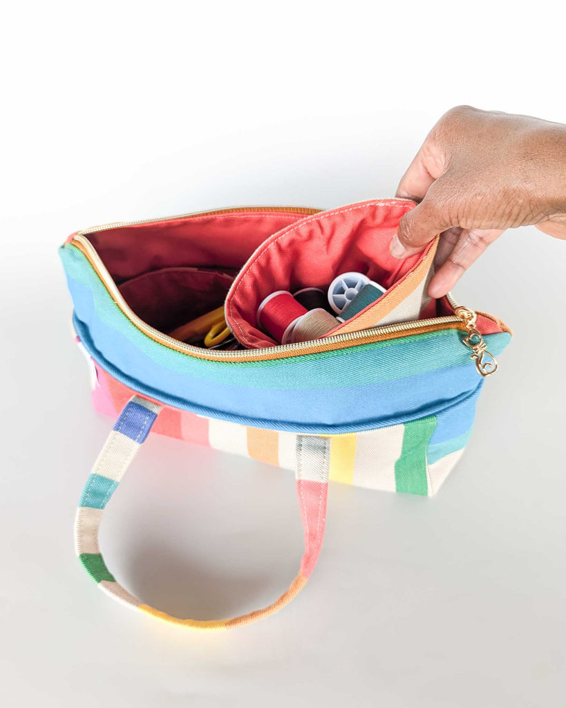 Main plaçant la pochette amovible à l’intérieur de la trousse Argia en tissu basque.