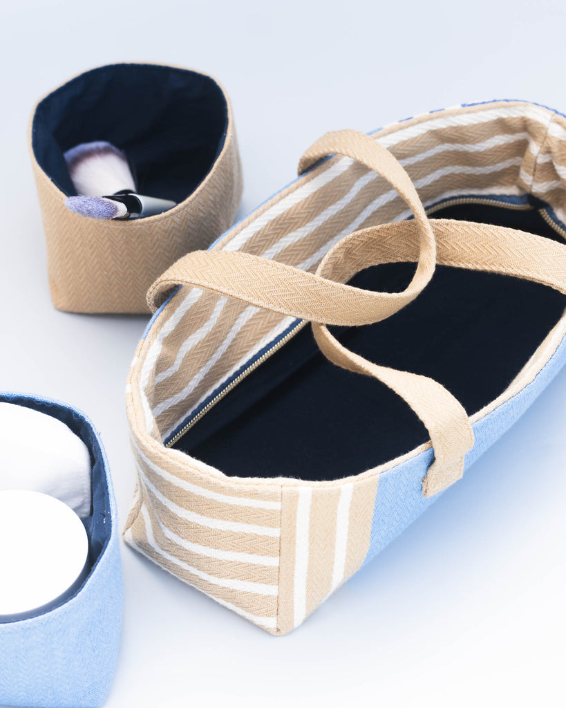  Intérieur de la trousse ouverte, révélant deux pochettes amovibles en toile beige et bleue, posées à côté. 