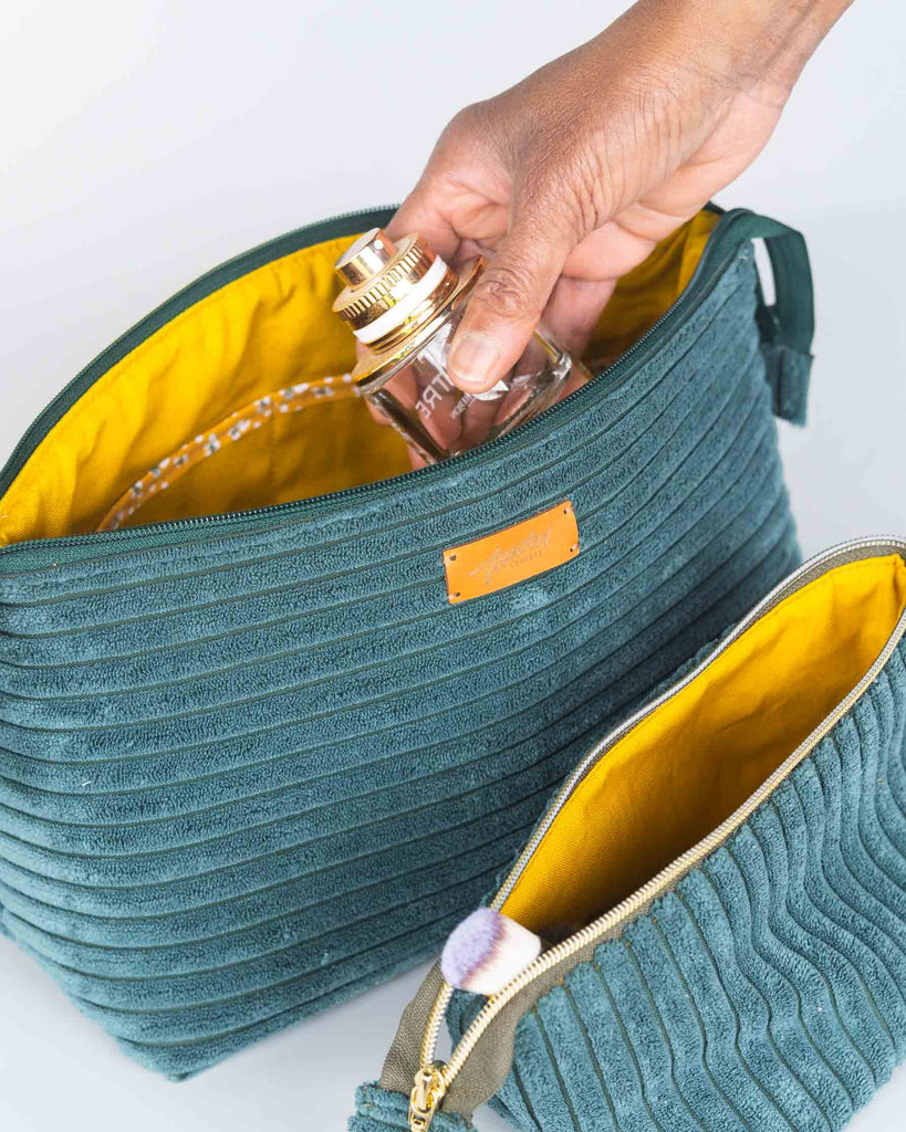 Trousse de toilette en tissu vert,main y déposant un flacon