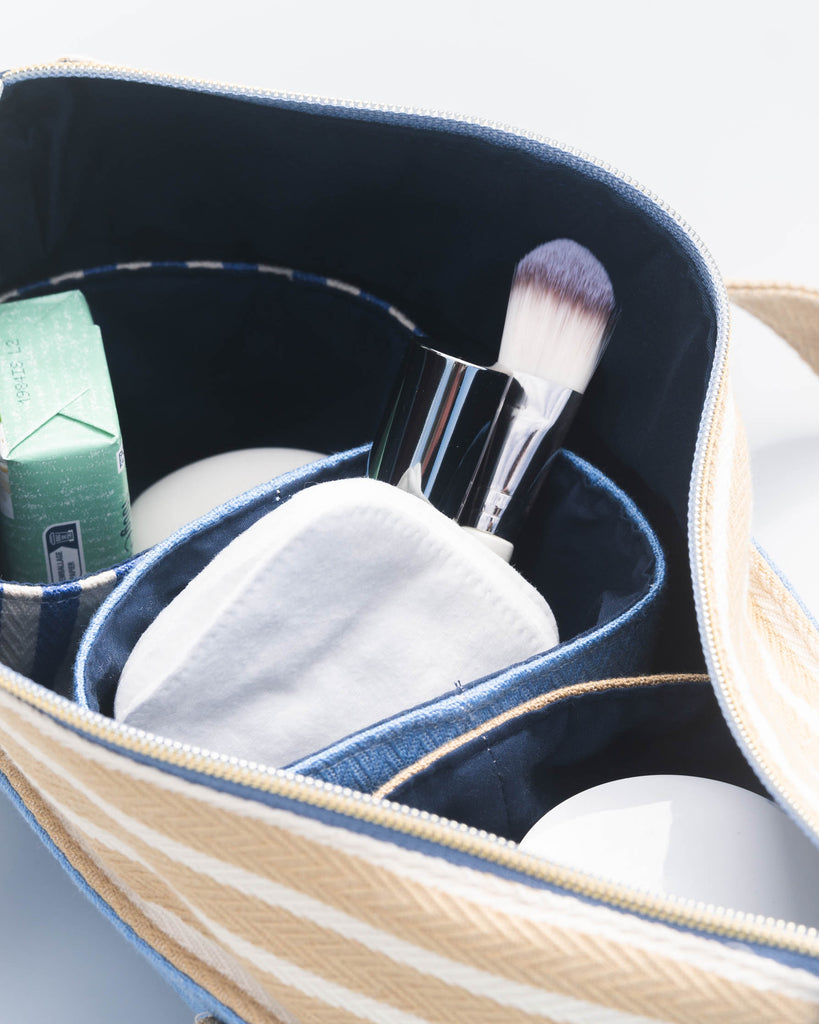  Intérieur de la trousse avec pinceau de maquillage, disque démaquillant, pot de crème et petite boîte. »